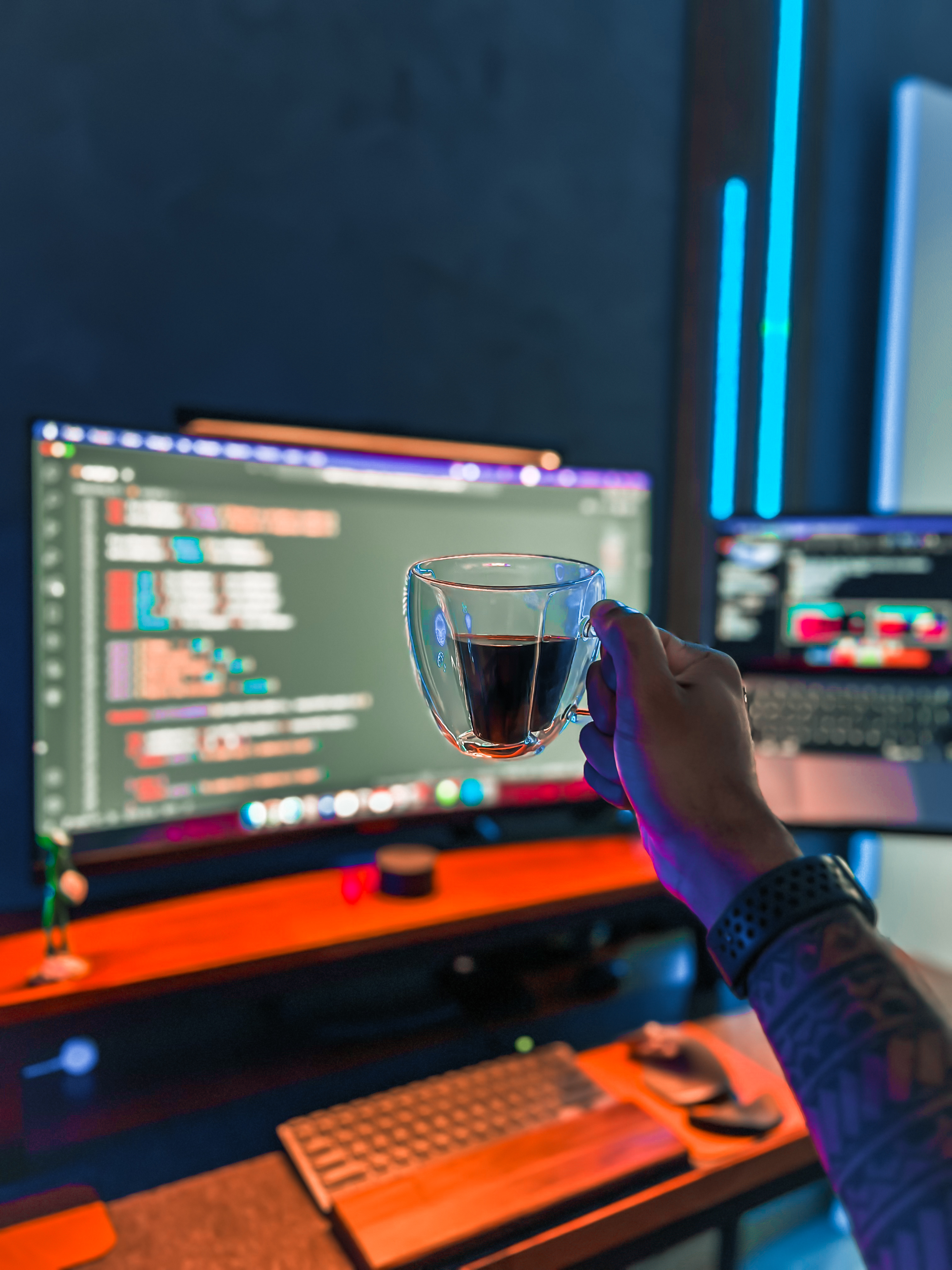 Imagem de 2 monitores exibindo código e uma xicara de café.